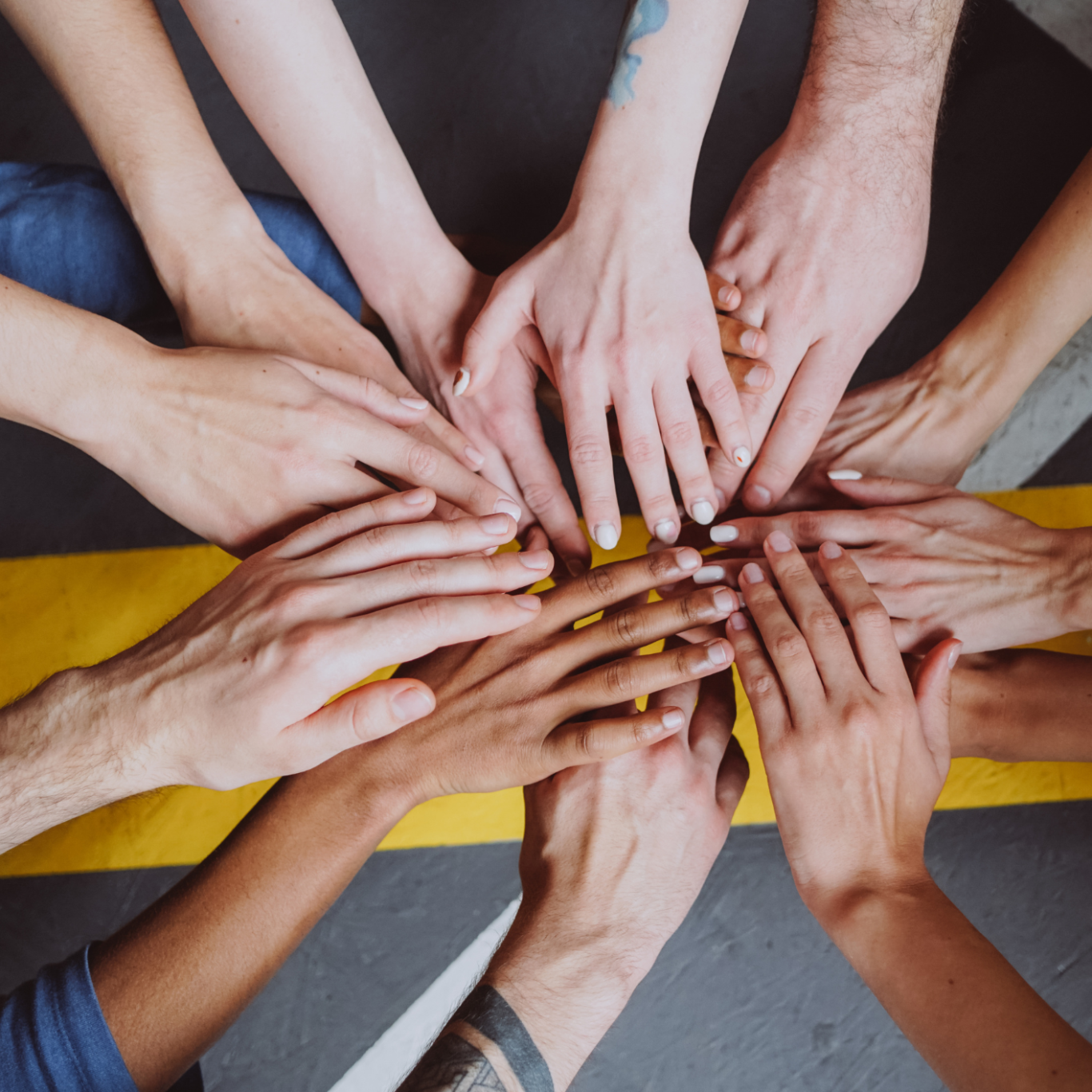 Hände verschiedener Menschen liegen aufeinander, um eine gemeinsame Verbindung darzustellen.