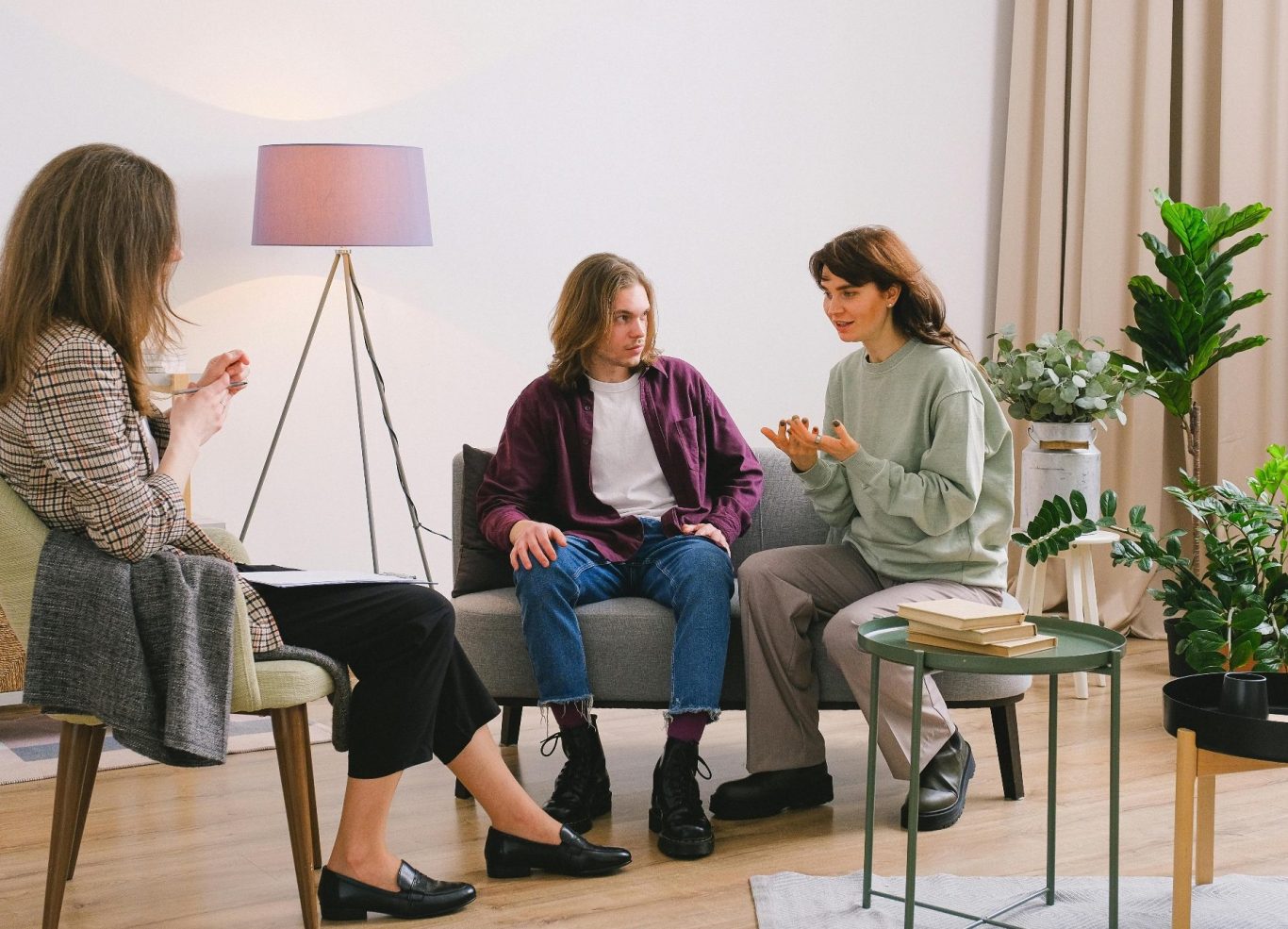 Zwei Frauen sitzen auf einem Sofa und sprechen, während eine dritte Person zuhört.