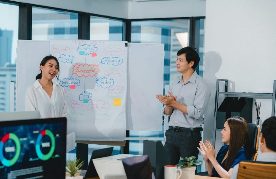 Personen besprechen ein Projekt vor einem Whiteboard in einem modernen Büro.