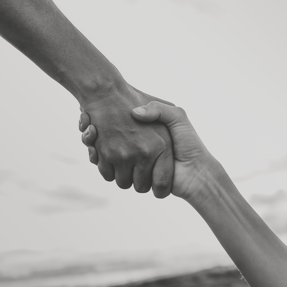 Zwei Hände greifen einander, eine robuste Hand und eine zartere Hand.